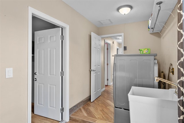 washroom with light wood-style flooring, washer / clothes dryer, a sink, and laundry area