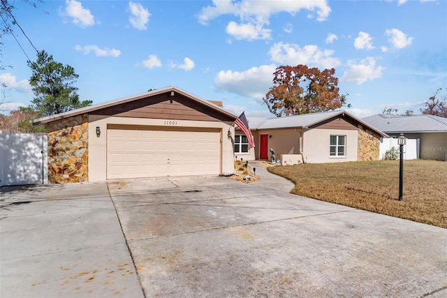 ranch-style home featuring driveway, stone siding, an attached garage, a front yard, and stucco siding