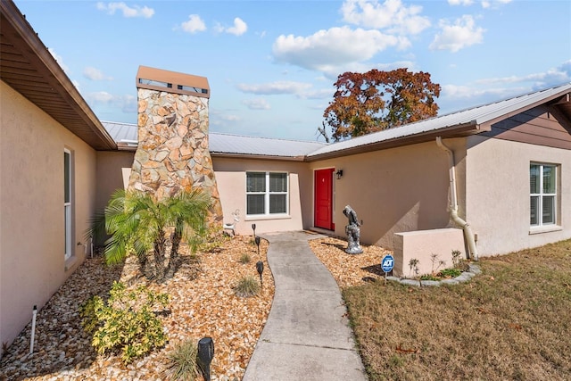 doorway to property with stucco siding and metal roof