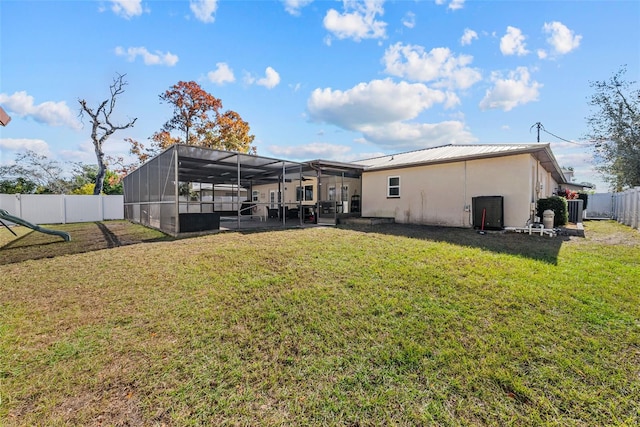 back of house with a fenced backyard, glass enclosure, stucco siding, a patio, and a lawn