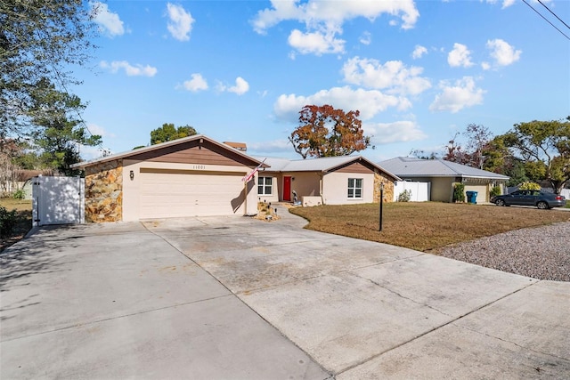 ranch-style home with stone siding, driveway, a front yard, and a garage