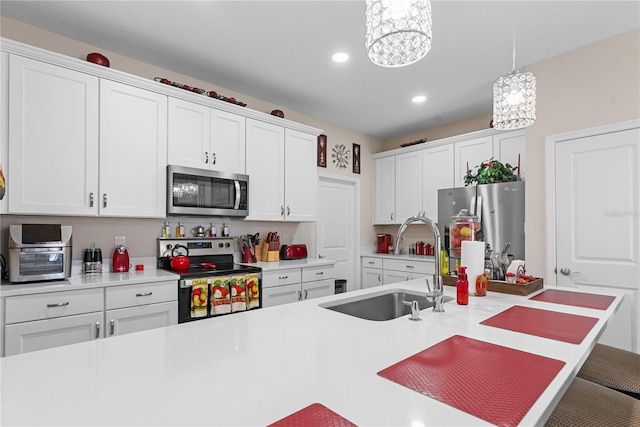 kitchen featuring white cabinetry, hanging light fixtures, stainless steel appliances, and sink