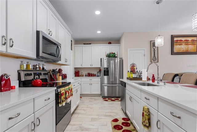 kitchen with sink, hanging light fixtures, white cabinets, and appliances with stainless steel finishes