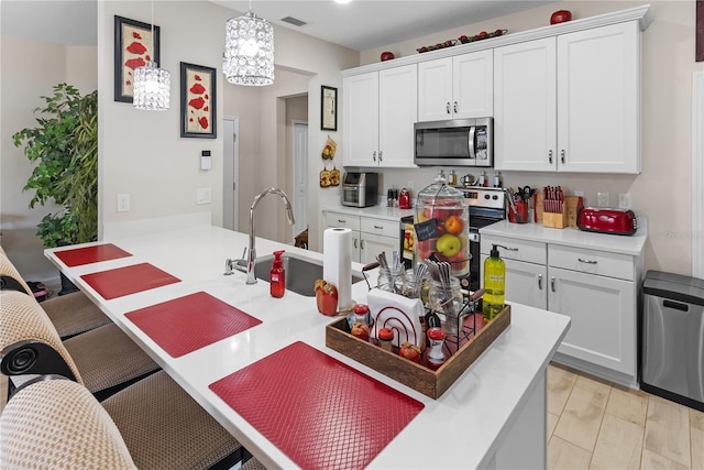 kitchen featuring stainless steel appliances, white cabinets, and decorative light fixtures