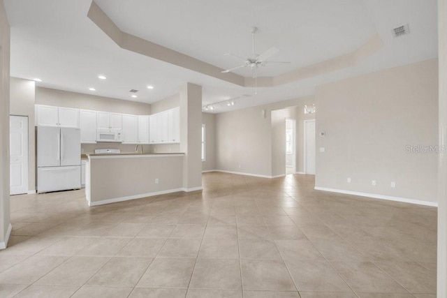 unfurnished living room featuring light tile patterned flooring, ceiling fan, and a tray ceiling