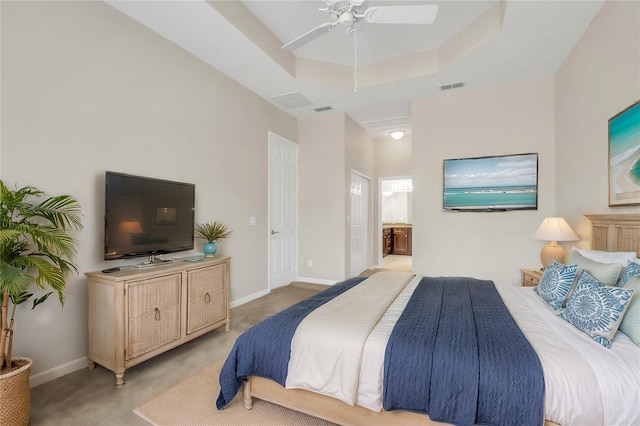 bedroom featuring light carpet, connected bathroom, ceiling fan, and a tray ceiling