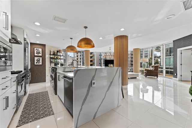 kitchen featuring a center island with sink, stainless steel appliances, pendant lighting, white cabinets, and sink