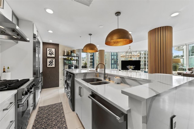 kitchen featuring white cabinets, wall chimney exhaust hood, decorative light fixtures, stainless steel appliances, and sink