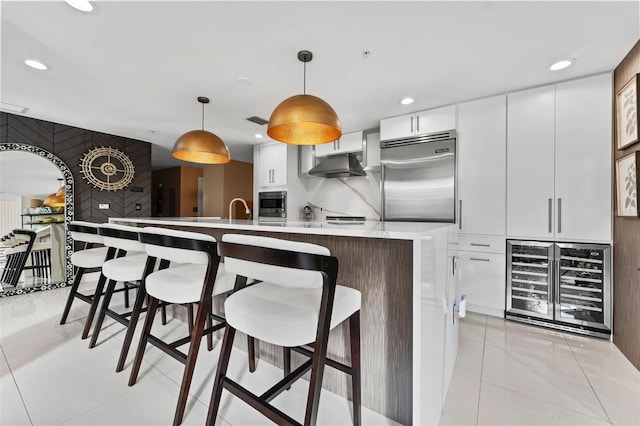 kitchen featuring light tile patterned floors, wine cooler, built in appliances, pendant lighting, and white cabinets