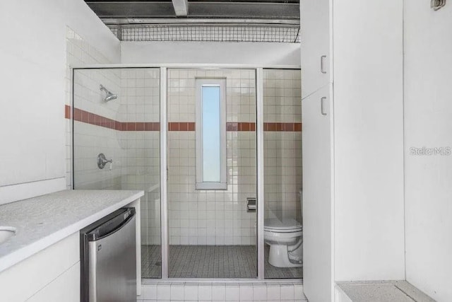 bathroom with toilet, vanity, and a shower with shower door