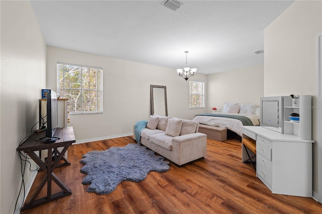 bedroom with hardwood / wood-style flooring, a chandelier, and multiple windows