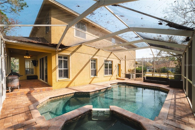 view of swimming pool featuring an outdoor hangout area, a patio area, glass enclosure, and an in ground hot tub