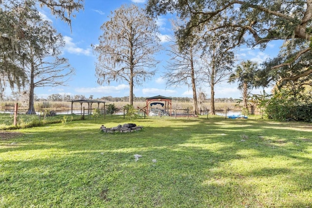 view of yard with a gazebo, a fire pit, and a water view