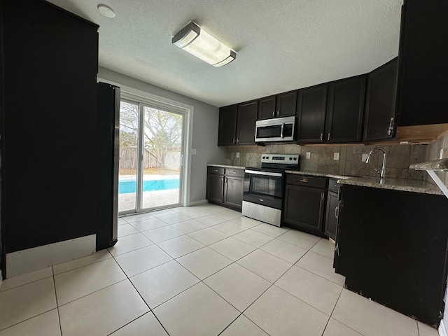 kitchen featuring sink, tasteful backsplash, light tile patterned floors, light stone countertops, and stainless steel appliances