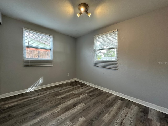 empty room with plenty of natural light and dark wood-type flooring