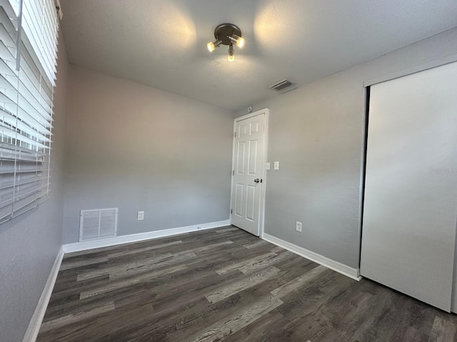 unfurnished bedroom with dark hardwood / wood-style flooring and a closet