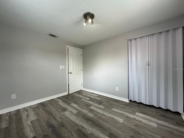 unfurnished bedroom with dark wood-type flooring and a textured ceiling