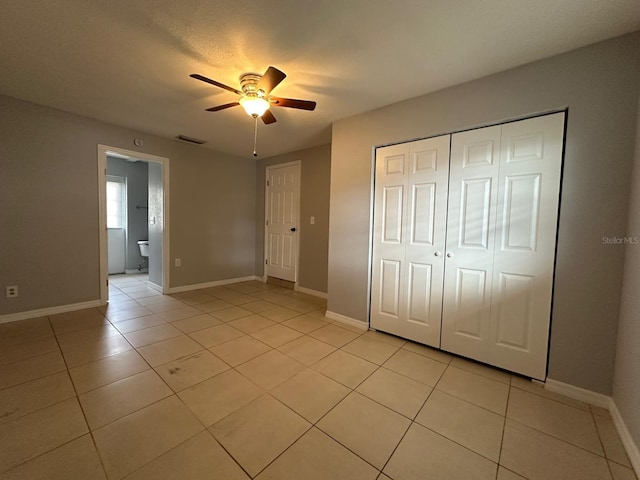 unfurnished bedroom featuring ceiling fan, ensuite bathroom, and light tile patterned floors