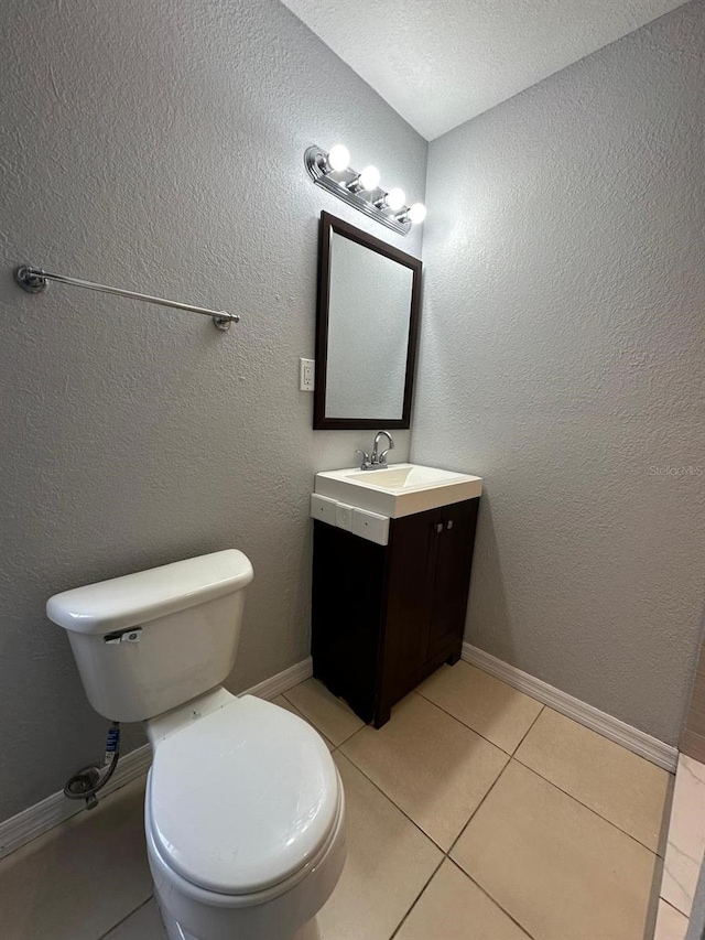 bathroom with a textured ceiling, toilet, tile patterned flooring, and vanity