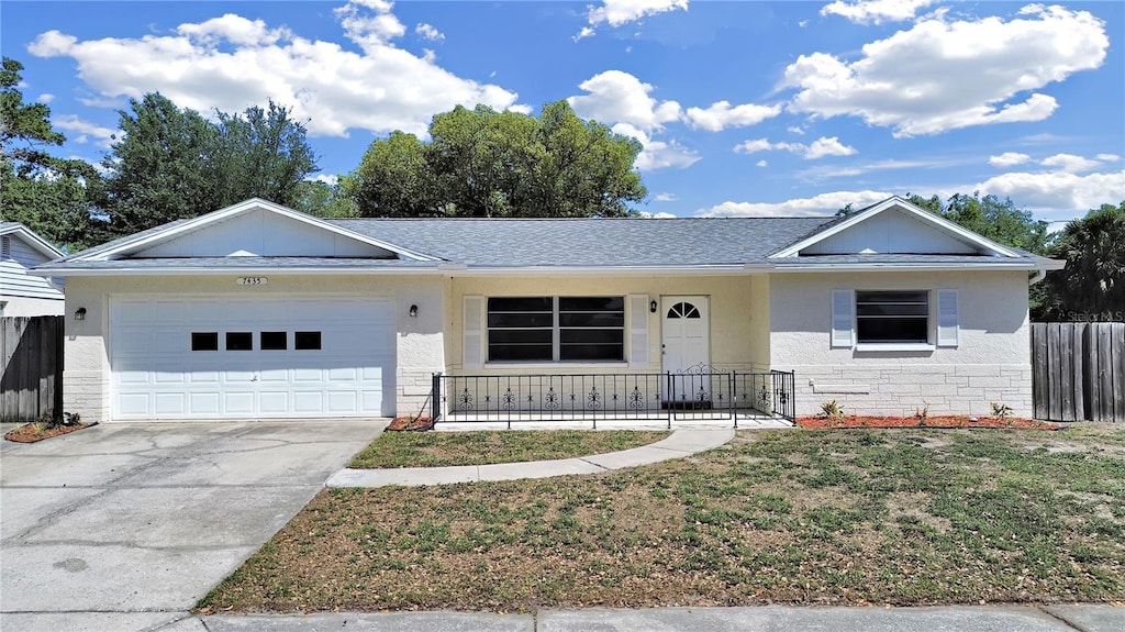 ranch-style house featuring concrete driveway, fence, stone siding, a front yard, and a garage