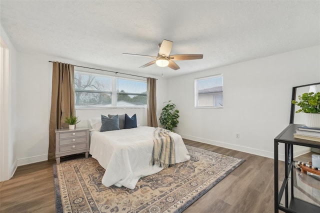 bedroom with ceiling fan, multiple windows, and dark hardwood / wood-style floors