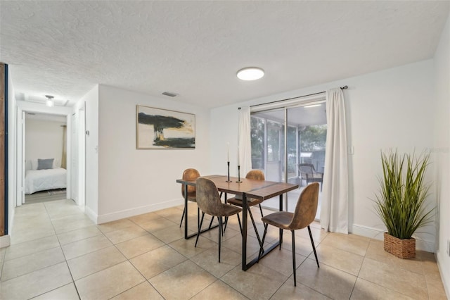 dining space featuring light tile patterned flooring and a textured ceiling