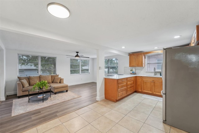 kitchen with ceiling fan, sink, tasteful backsplash, light hardwood / wood-style floors, and stainless steel refrigerator