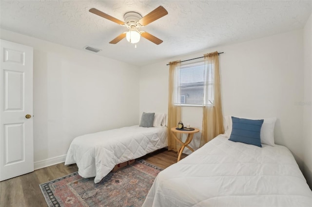 bedroom featuring hardwood / wood-style flooring, a textured ceiling, and ceiling fan