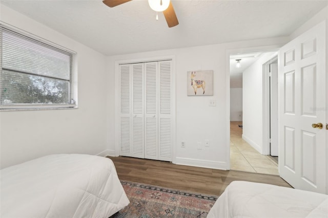 bedroom with a closet, ceiling fan, hardwood / wood-style floors, and a textured ceiling