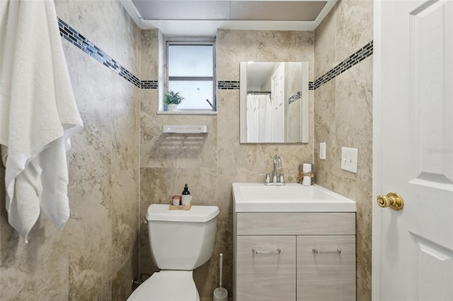 bathroom featuring vanity, toilet, and tile walls