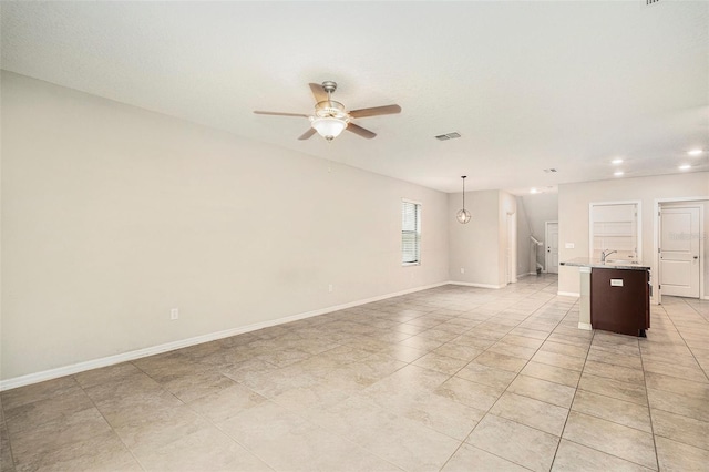 tiled empty room featuring ceiling fan and sink