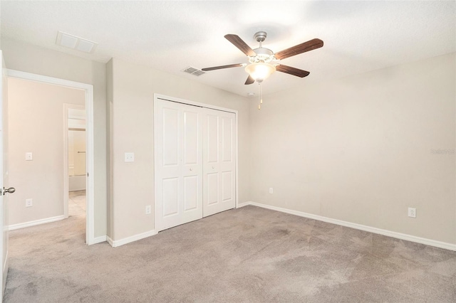 unfurnished bedroom featuring ceiling fan, light colored carpet, and a closet