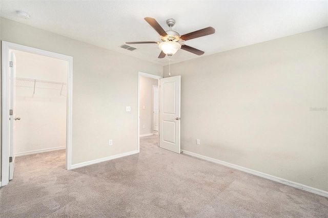 unfurnished bedroom featuring a spacious closet, a closet, and ceiling fan