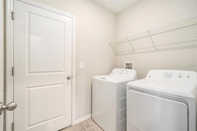 clothes washing area featuring light tile patterned floors and washer and dryer