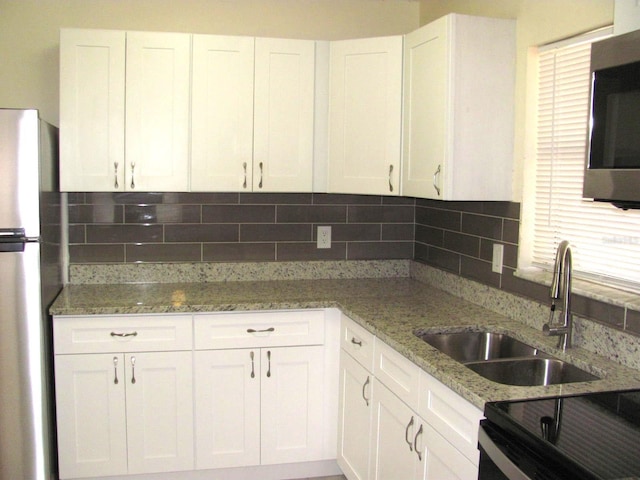 kitchen featuring sink, white cabinets, tasteful backsplash, light stone counters, and stainless steel appliances