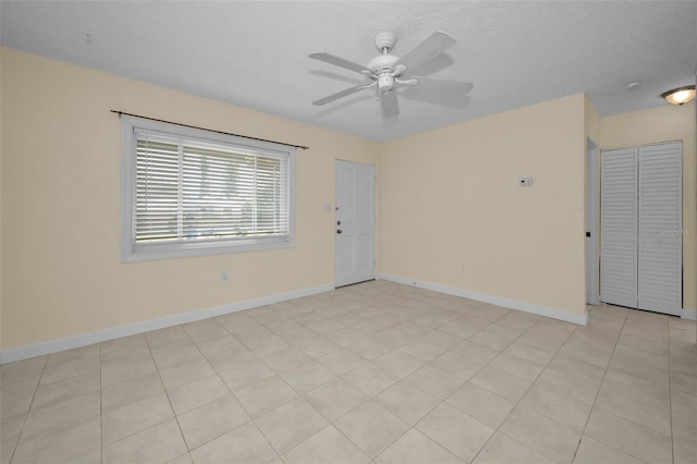 tiled spare room featuring a textured ceiling and ceiling fan