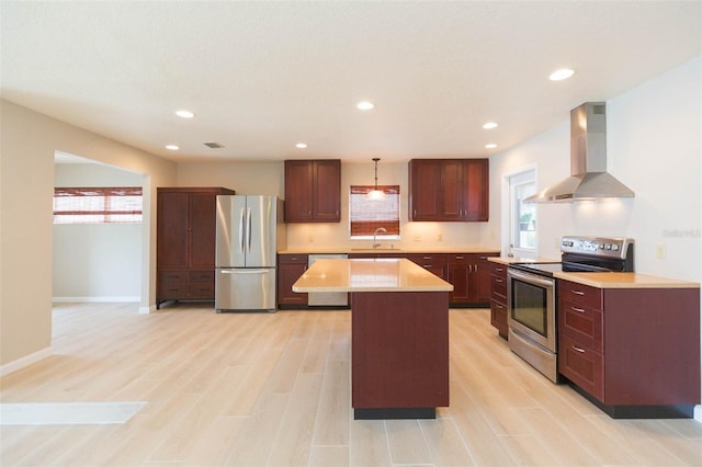 kitchen featuring a center island, sink, hanging light fixtures, stainless steel appliances, and wall chimney exhaust hood