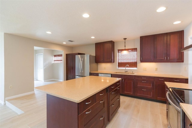 kitchen featuring decorative light fixtures, sink, appliances with stainless steel finishes, and a kitchen island