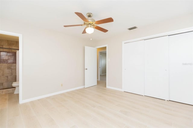 unfurnished bedroom featuring ceiling fan, a closet, and ensuite bath