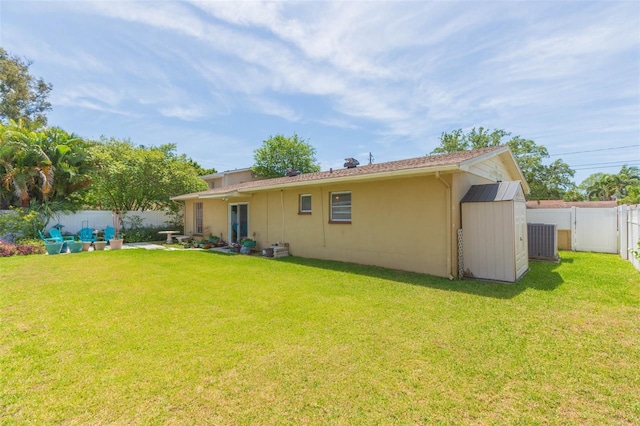 back of house featuring a lawn, cooling unit, and a storage unit