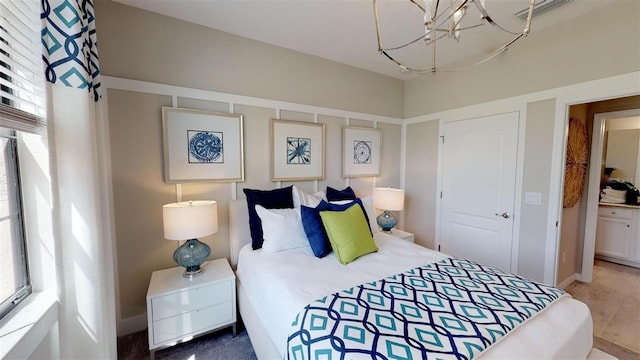 bedroom with ensuite bath and a chandelier