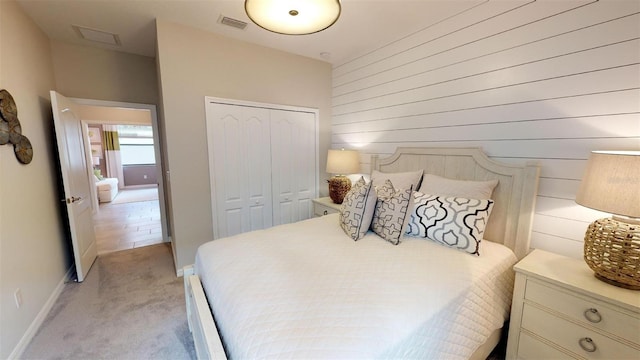 bedroom featuring light carpet, wooden walls, and a closet