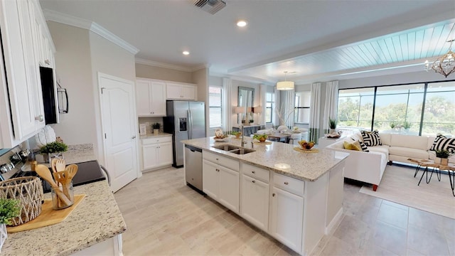 kitchen featuring appliances with stainless steel finishes, decorative light fixtures, white cabinetry, sink, and a center island with sink