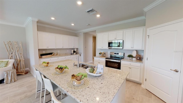 kitchen with white cabinetry, appliances with stainless steel finishes, sink, and a center island with sink