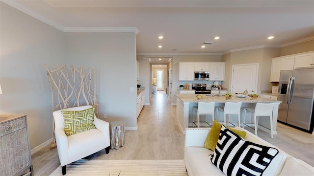 kitchen featuring white cabinetry, light stone countertops, stainless steel appliances, and an island with sink