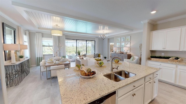 kitchen with white cabinetry, decorative light fixtures, sink, and light stone counters