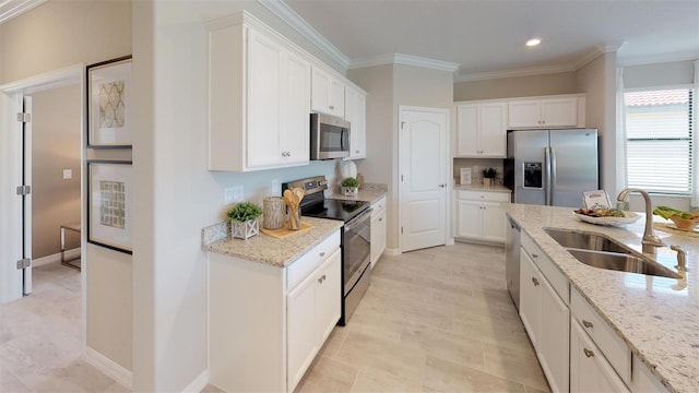 kitchen with white cabinetry, appliances with stainless steel finishes, light stone countertops, and sink