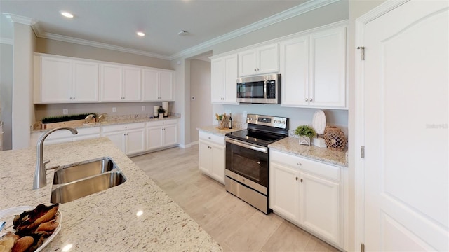 kitchen with stainless steel appliances, sink, white cabinets, and light stone counters