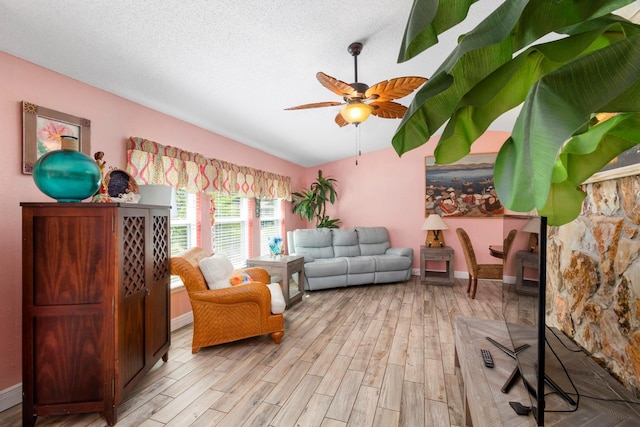 living area featuring ceiling fan, a textured ceiling, vaulted ceiling, and light wood-type flooring