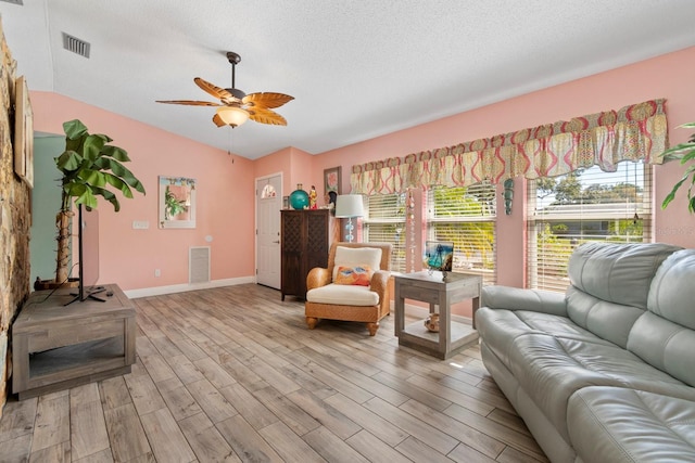 sitting room with ceiling fan, a textured ceiling, vaulted ceiling, and light wood-type flooring